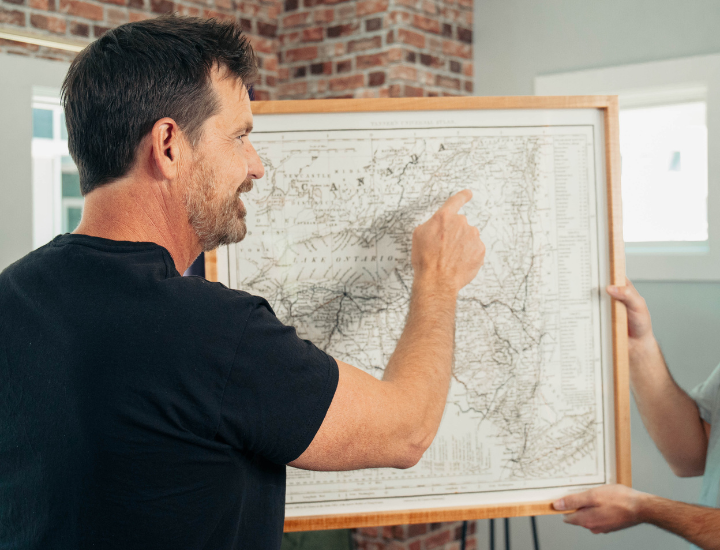 A framed vintage map being positioned on a wall